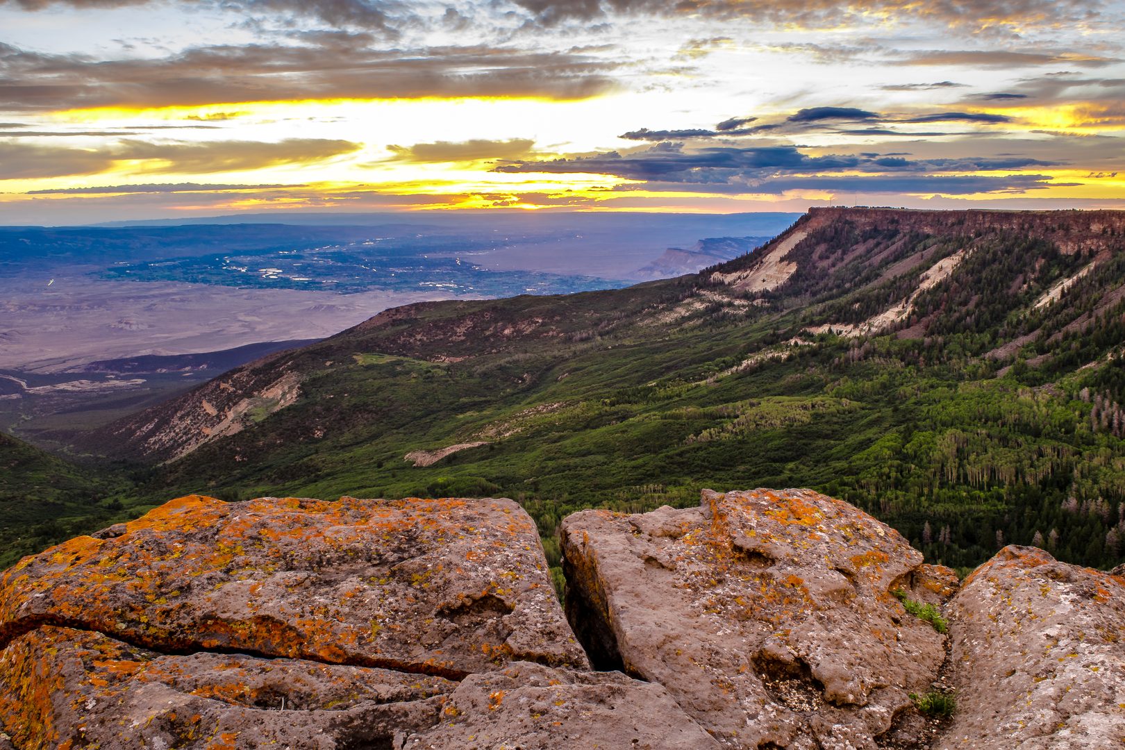 Sunrise view from the Grand Mesa, Colorado — orange lichen rocks and golden sky